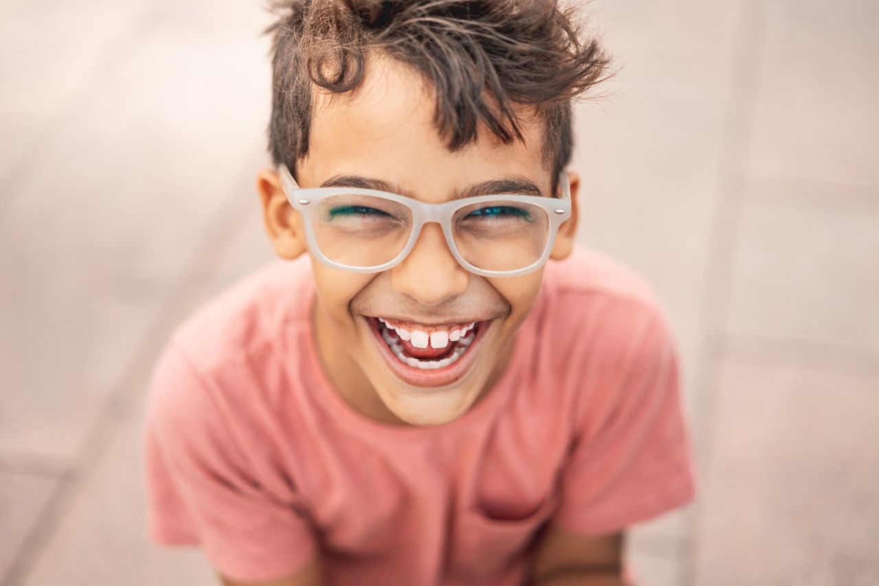 Photographie d'un garçon adolescent qui sourit en montrant ses dents 